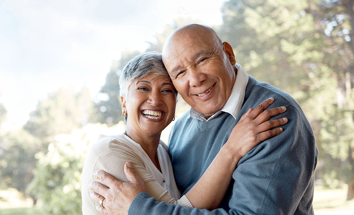 Smiling older couple with arms around each other.